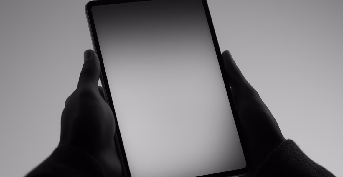 Hands holding a tablet with a blank screen, in black and white